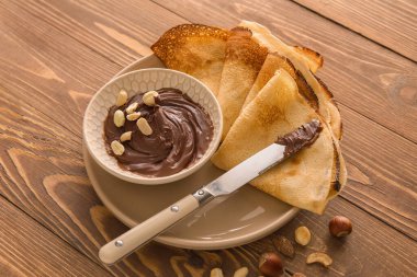 Tahta arka planda çikolata ezmeli ve fındıklı lezzetli ince krepler.