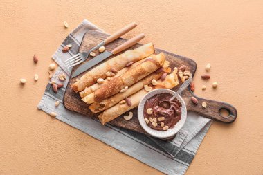 Tahta ahşap tahta, üzerinde çikolata ezmesi ve fındık olan ince krepler.