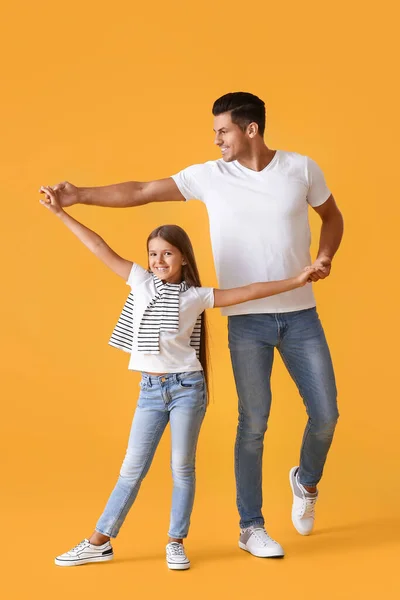 Happy dancing man and his daughter on color background