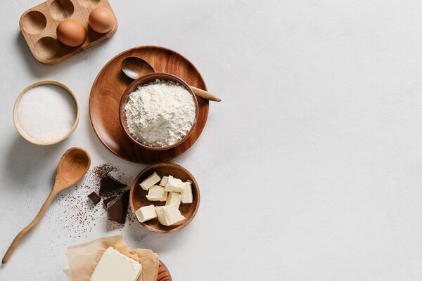 Bowl with flour and ingredients for preparing chocolate brownie on white background