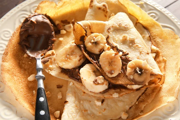 Plate Tasty Thin Pancakes Chocolate Paste Cut Banana Nuts Table — Zdjęcie stockowe
