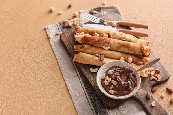 Wooden Board Tasty Thin Pancakes Chocolate Paste Nuts Beige Background — Fotografia de Stock