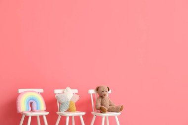 Chairs with cute toys on color background
