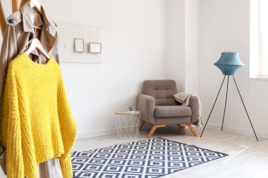 Interior of light living room with soft armchair, table and standing lamp
