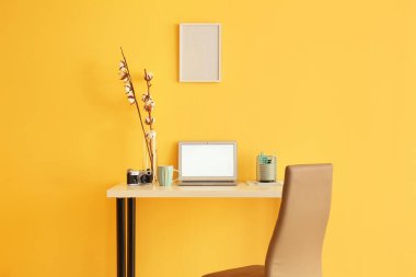 Workplace with modern laptop, vintage photo camera and cup near color wall