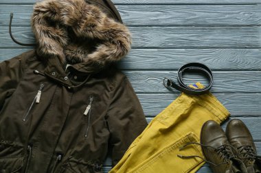 Stylish jacket, pants, belt and shoes on grey wooden background