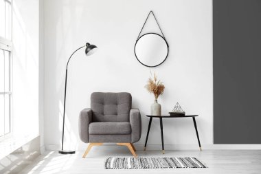 Rahat koltuğu, lambası ve ışık duvarının yanındaki masası olan bir oda.