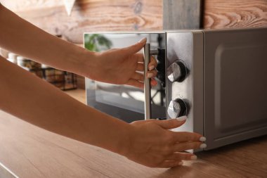 Mutfakta mikrodalga fırın açan kadın, yakın plan.