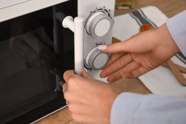 Mutfakta mikrodalga fırın kullanan kadın, yakın plan.