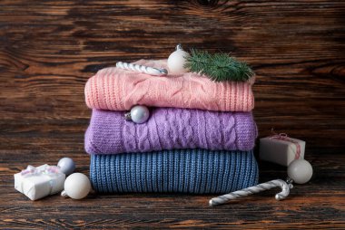 Şık bebek kazakları ve ahşap arka planda Noel süslemeleri.