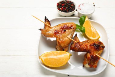 Izgara tavuk kanatlı tabak şiş ve beyaz ahşap arka planda limon.
