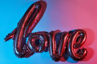 Renkli arka planda aşk kelimesi şeklinde bir balon. Sevgililer Günü kutlaması
