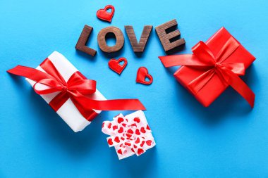 Sevgililer Günü hediyeli kompozisyon ve mavi arka planda aşk kelimesi.