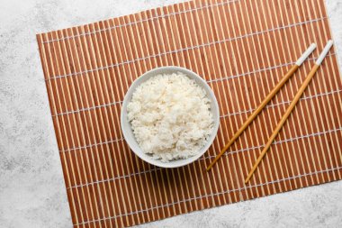 Lezzetli haşlanmış pirinç ve hafif arka planda çubuklarla dolu bir kase.