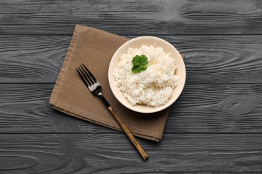 Koyu ahşap arka planda lezzetli haşlanmış pirinç kasesi.