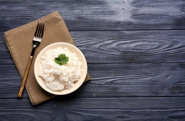 Koyu ahşap arka planda lezzetli haşlanmış pirinç kasesi.