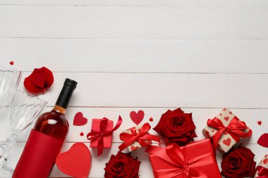 Hafif ahşap arka planda Sevgililer Günü için şarap, hediye ve güller içeren kompozisyon