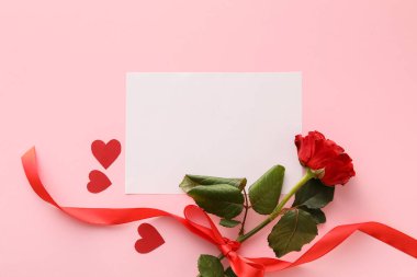 Üzerinde pembe arka planda gül çiçeği ve boş bir kart olan kompozisyon. Sevgililer Günü kutlaması