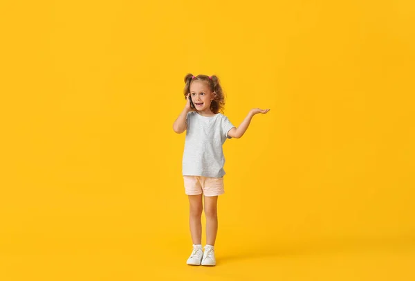 Sarı Arka Planda Cep Telefonuyla Konuşan Sevimli Küçük Kız — Stok fotoğraf