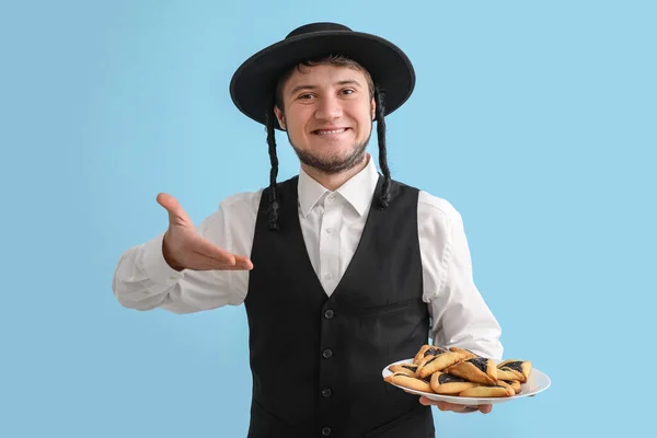 Young Jewish Man Tasty Hamantaschen Purim Holiday Color Background — Fotografia de Stock