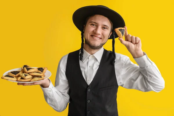 Young Jewish Man Tasty Hamantaschen Purim Holiday Color Background — Fotografia de Stock