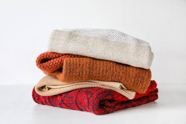 Stylish baby sweaters on light background