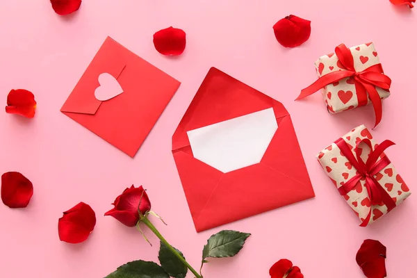 Composition with envelopes, card, gifts and rose petals on color background. Valentine\'s Day celebration