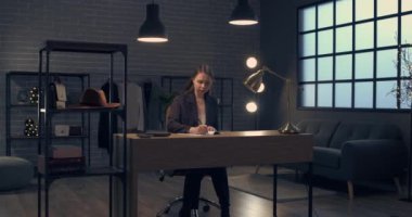 Karanlık ofisteki masada çalışan genç moda tasarımcısı.