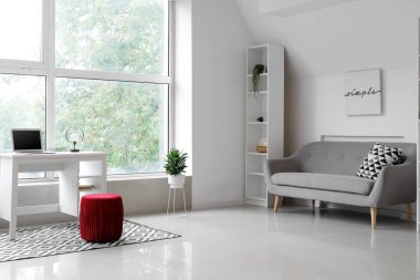 Kanepesi ve kırmızı pouf 'u olan bir oturma odası.