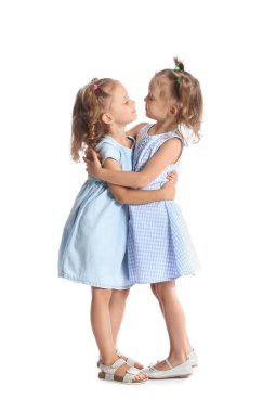 Beyaz arka planda sarılan sevimli küçük kız kardeşler.