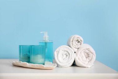 Kozmetik ürünleri olan temiz havlular ve mavi duvarın yanındaki rafta mumlar.