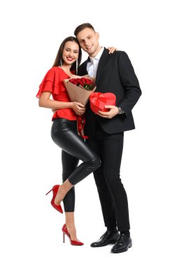 Beyaz arka planda bir buket çiçek ve hediyeyle mutlu genç bir çift. Sevgililer Günü kutlaması