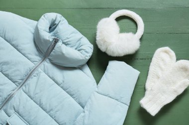 Kışlık ceket, eldivenler ve yeşil ahşap arka planda kulaklık.