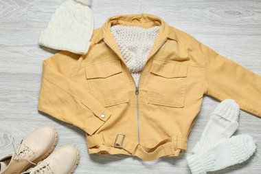 Kadın ceketi, örgü şapka, eldivenler ve gri ahşap arka planda ayakkabılar.