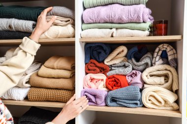 Gardıroptaki raftan sıcak kazak alan kadın, yakın plan.