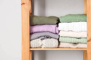 Kalın kazaklı raf ünitesi, ışık duvarının yanında, yakın plan.