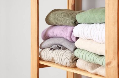 Rafta, ışık duvarının yanında, sıcak örülmüş süveterler.