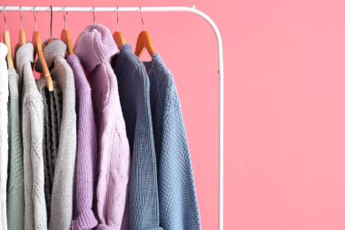 Pembe duvarın yanında şık ve kalın kazaklar var.