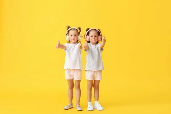 Słodkie Małe Dziewczynki Słuchawki Pokazując Kciuki Górę Żółtym Tle — Zdjęcie stockowe