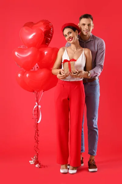 Jovem Casal Feliz Com Presente Balões Fundo Vermelho Celebração Dia — Fotografia de Stock