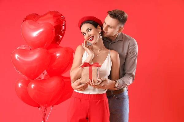 Šťastný Mladý Pár Dárkem Balónky Červeném Pozadí Valentýnská Oslava — Stock fotografie