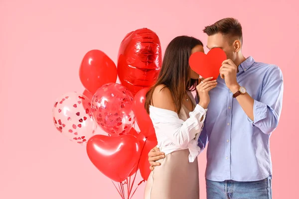 色の背景に赤いハートと風船を持つ幸せな若いカップル バレンタインデーのお祝い — ストック写真