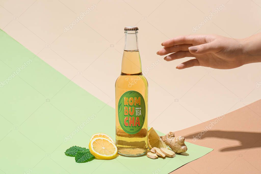 Female hand with natural kombucha on color background