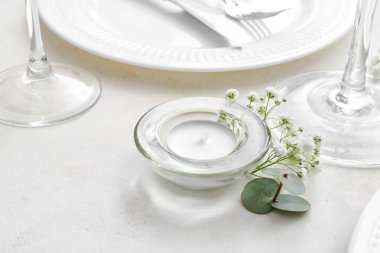 Işık arkaplanda mum ve çiçek dekoru ile güzel masa ayarları, yakın plan