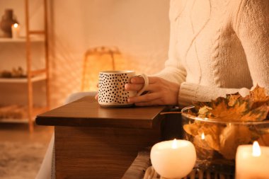 Bir fincan kahve ve sonbahar yapraklı kadın evde, yakın çekim.