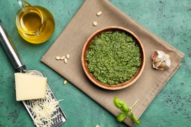 Bir kase lezzetli pesto sosu ve yeşil arka planda malzemeler.