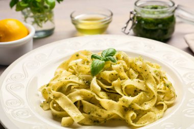 Hafif ahşap zemin üzerinde bir tabak lezzetli pesto makarna.