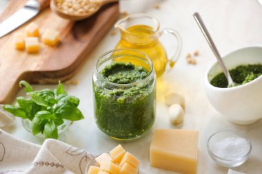 Kavanoz dolusu pesto sosu ve hafif arka planda malzemeler.