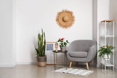 Koltuğu, raf ünitesi ve masasının üzerindeki saksıda Anthurium çiçeği olan ışık odasının içi.