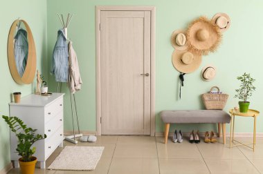 Koridorun içinde çekmeceler, banklar, hasır şapkalar ve ceketli askılar var.